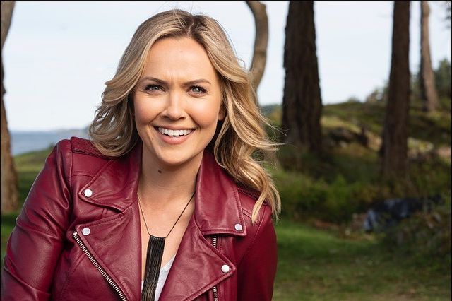 Emilie Ullerup smiling in a red leather jacket and black leather jewelry.